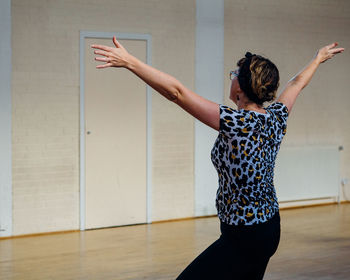 Woman with arms outstretched dancing on hardwood floor at studio