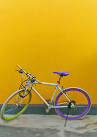 Bicycle parked against yellow wall