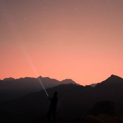 Silhouette man standing on mountain against sky during sunset