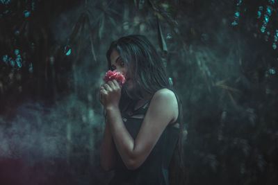 Side view of a young woman standing against plants