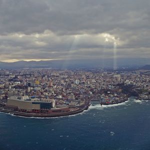 Aerial view of city by sea against sky