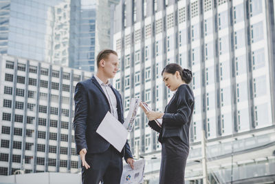 Business people discussing while standing against building