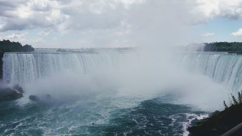 Scenic view of waterfall against sky