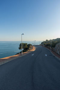 Road by sea against clear sky