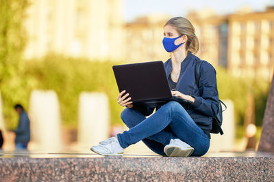 Full length of young woman using mobile phone