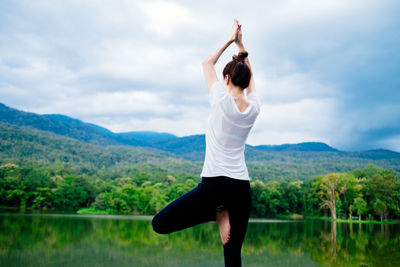 Rear view of woman with arms raised against mountain