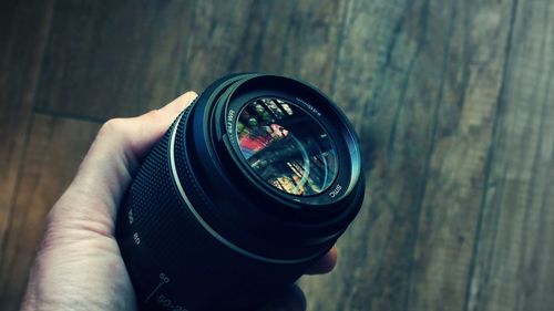 Cropped hand holding camera on wooden table