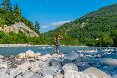 Man standing on rocks by mountain against sky