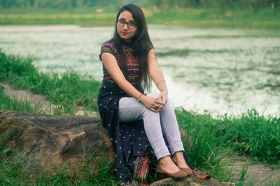 Portrait of young woman sitting on rock