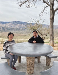 Portrait of a couple sitting on a table behind the scenery view 