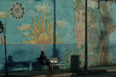 People sitting on chair by table against wall