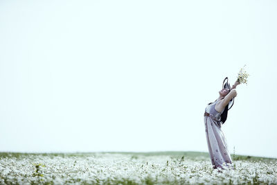 Low angle view of woman standing on field against clear sky