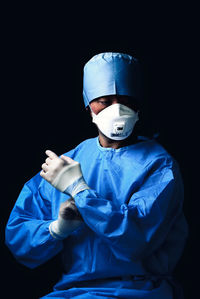 Portrait of man wearing mask against black background