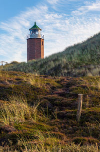 Lighthouse on field against sky