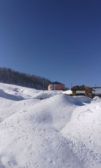 Snow covered landscape against clear blue sky