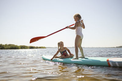 Girls having fun on stand up paddleboard at lake