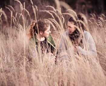 Friends talking while sitting on field