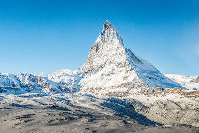 Scenic view of snowcapped mountains against clear blue sky