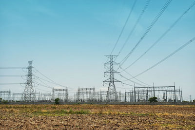 Low angle view of electricity pylon on field against sky