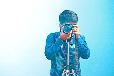 Man photographing against blue sky