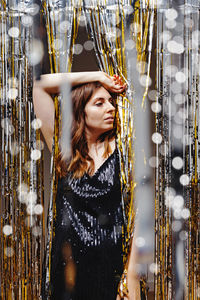 New year's eve party concept. woman in sequins dress partying. festive decor and blurred lights