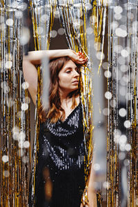 Portrait of young woman standing against christmas tree