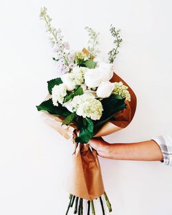 Low angle view of woman holding bouquet against white background