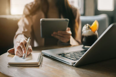 Midsection of woman using laptop at table