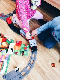 Low section of children playing with toy train at home