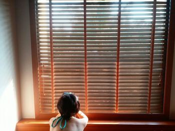 Rear view of woman by window