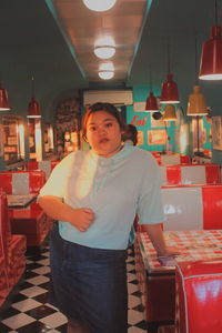 Portrait of man standing at illuminated restaurant