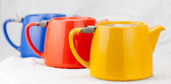 Close-up of colorful kettles against white background