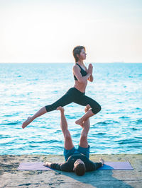 Couple doing yoga by sea