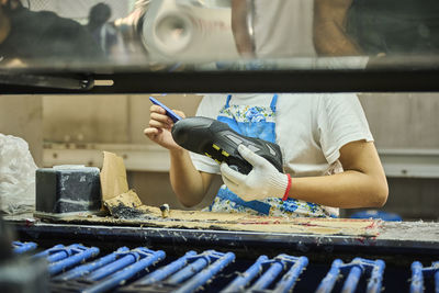 Detail of worker applying glue to the shoes sole in a production line of chinese shoes factory