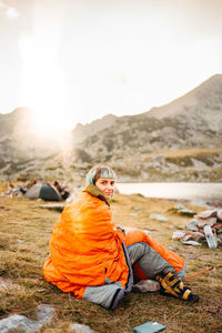 Portrait of woman sitting on rock against mountain