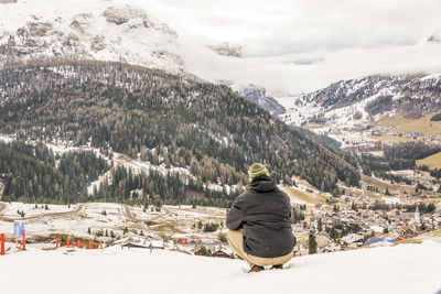 Rear view of woman sitting on snowcapped mountain