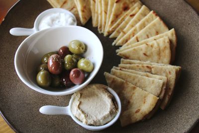High angle view of olives and humus in bowl on table