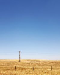Wind turbines on field against clear blue sky