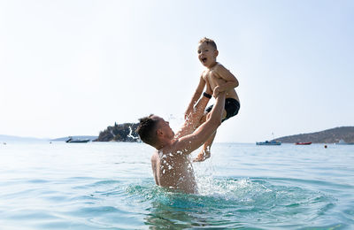 Full length of shirtless man swimming in sea