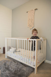 Portrait of cute toddler girl standing inside her crib