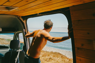 Rear view of shirtless man on beach