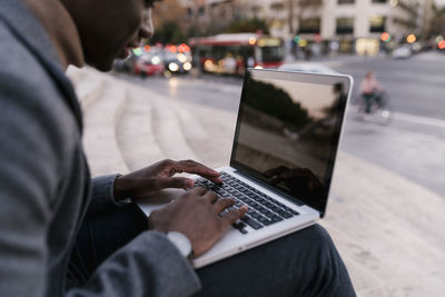 Young man using laptop while sitting outdoors