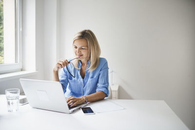 Young woman using phone while sitting on table