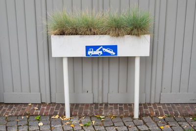 Information sign on footpath against wall