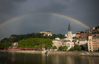 Scenic view of rainbow over river and buildings in lyon city