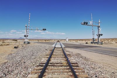 Railroad tracks crossing road against sky