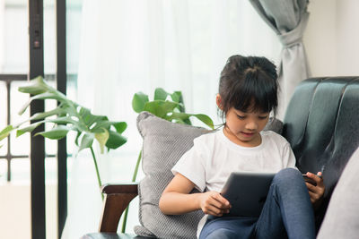 Young woman using mobile phone while sitting on sofa