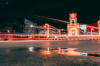 Illuminated building by river against sky in city at night