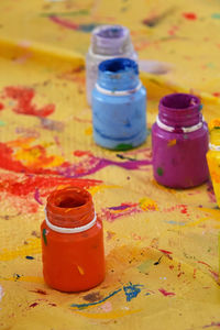 High angle view of colorful paint bottles on messy paper
