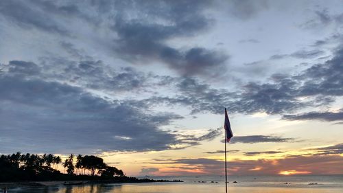 Scenic view of sea against cloudy sky at sunset